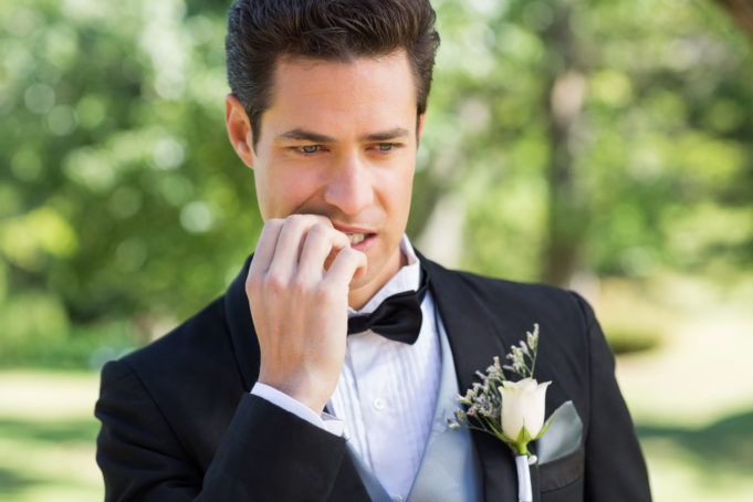 Closeup of young groom biting nails in garden